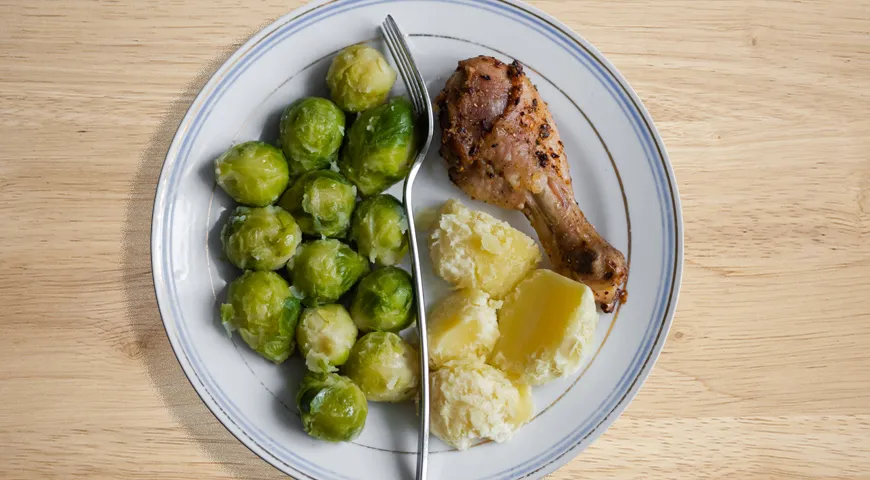 Гарвардская тарелка питания на практике:  50% овощи, богатые клетчаткой (например, брюссельская капуста),  25% белок (куриная ножка) и 25% богатые крахмалом овощи (картошка)