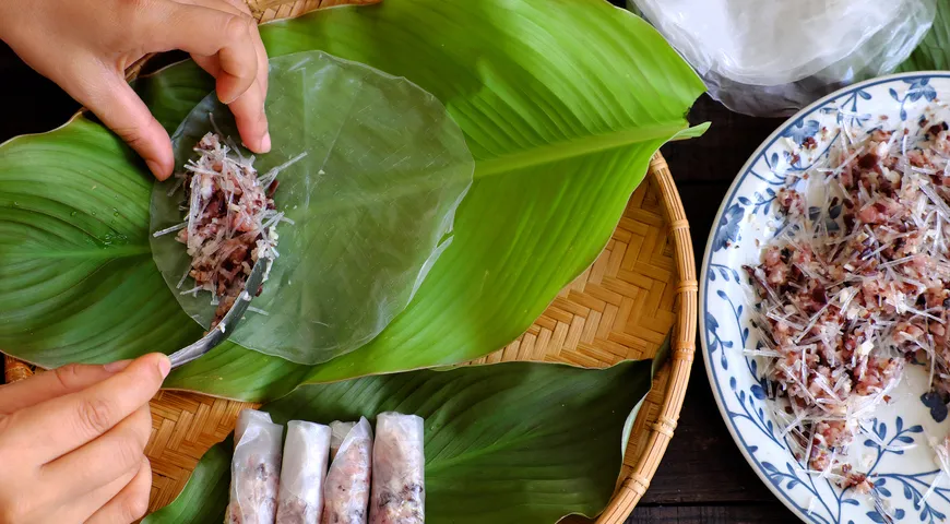 Рисовую бумагу сначала быстро окунают в воду, чтобы сделать мягкой, а потом выкладывают начинку