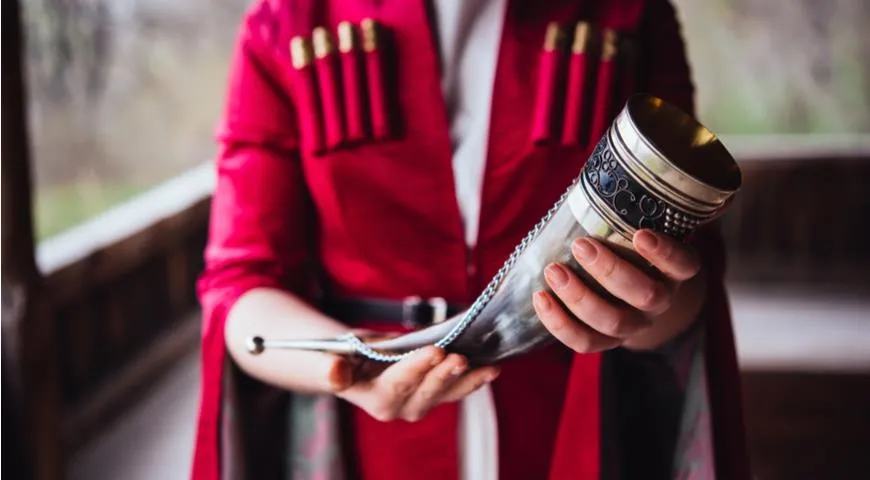 Грузин держит в руках рог с вином