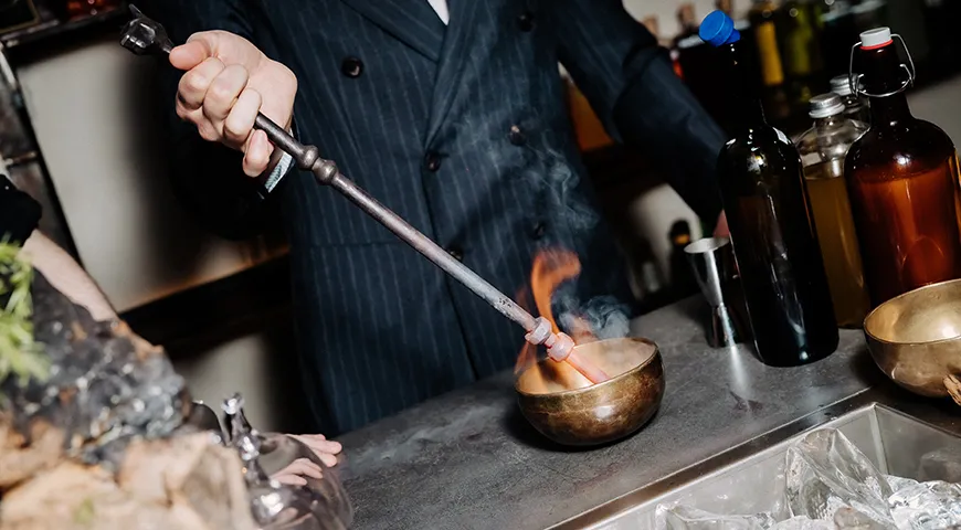 Бармен опускает в коктейль раскаленную кочергу, в результате напиток обретает вкус и аромат жженной ириски, хлебной корки, дымка