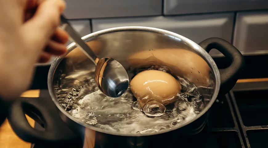 Яйца аккуратно опускают в кипящую воду ложкой, чтобы не повредить скорлупу