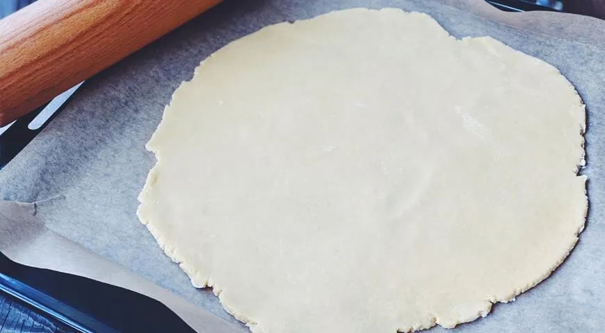 Раскатайте тесто  и перенесите его на противень, застеленный бумагой для выпечки