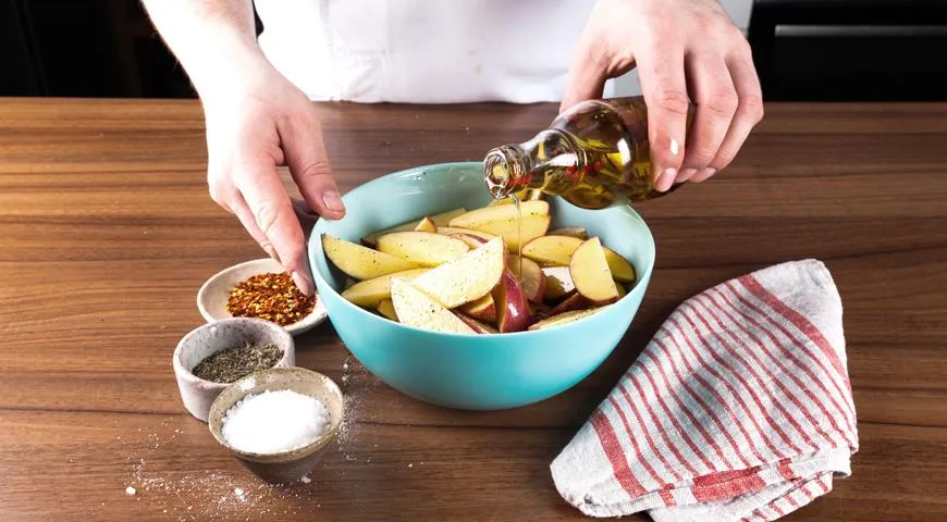 Добавьте к картофелю специй и полейте оливковым маслом