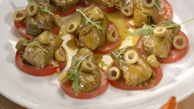 Козий сыр в виноградных листьях с томатами и оливками