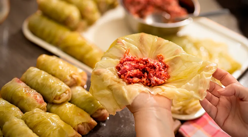 Чтобы голубцы получились идеальной формы, выложите фарш на середину листа и сверните его в плотный рулетик