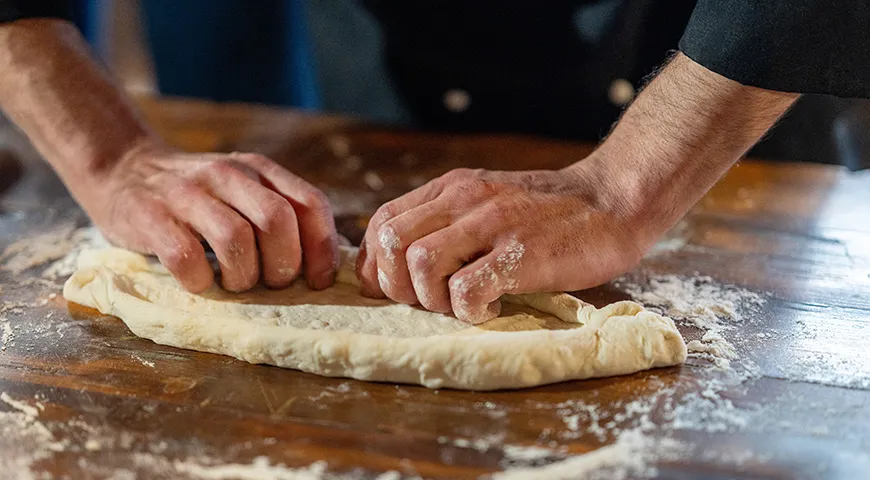 Чтобы сформировать бортики хачапури, подверните края с двух длинных сторон к центру рулетом