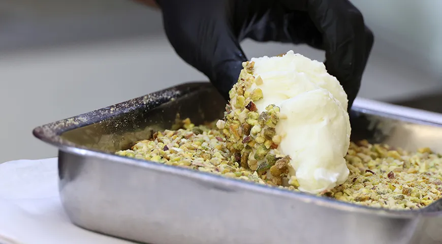 Перед обжаркой шарики мороженого обваливают в хрустящих крошках (например, в ореховых)