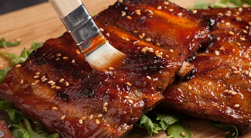 Чтобы на свиных ребрышках получилась красивая блестящая корочка, за 20–30 минут до окончания копчения смажьте их медом, кленовым сиропом или соусом барбекю