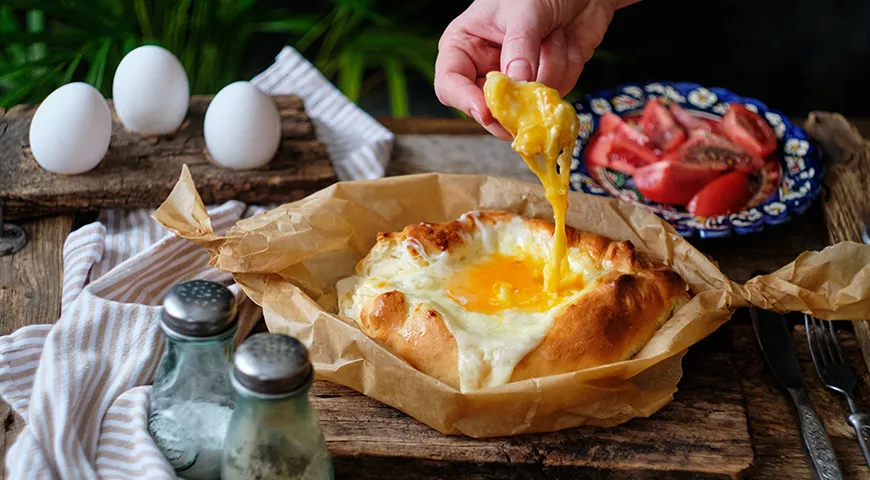 Хачапури по-аджарски принято есть руками. Отламывают кусочек бортика «лодочки», перемешивают им яйцо, сыр и масло и отправляют в рот