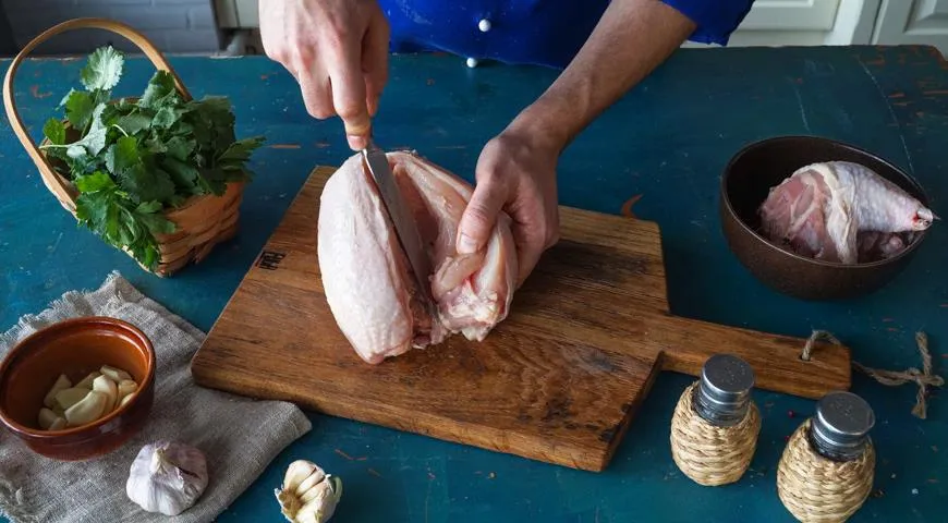 Прорежьте курицу посередине груди вдоль с двух сторон от килевой кости