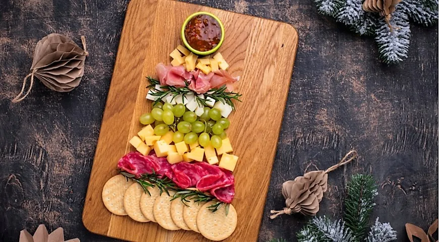 Демократичный вариант Charcuterie board из мясной нарезки, сыра и винограда в форме ёлки для праздничного стола