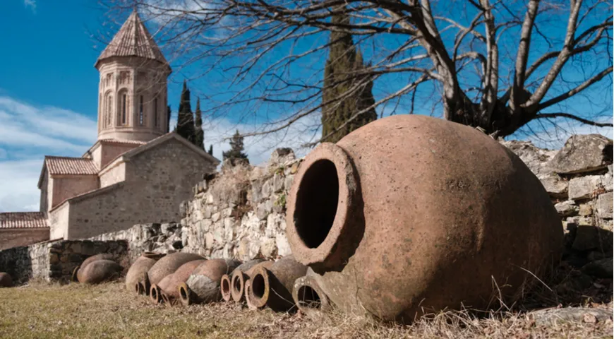 Квеври, традиционный грузинский кувшин для хранения вина у монастырской стены