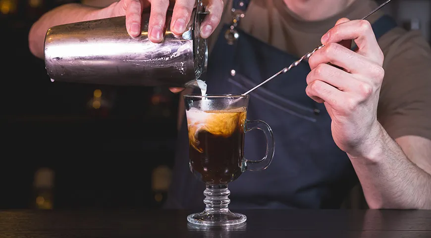 Ирландский кофе подают в стеклянном бокале на ножке, чтобы подчеркнуть контраст горячей основы и холодных сливок