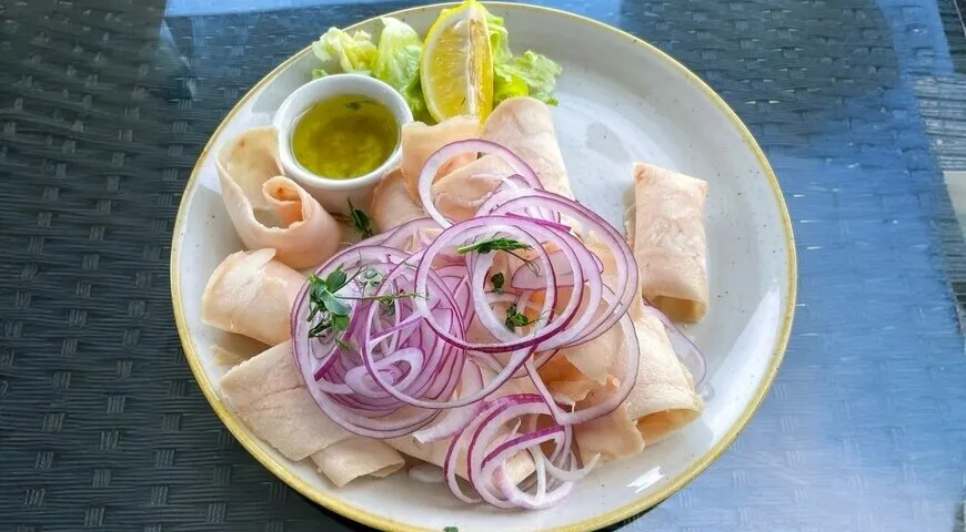 Строганина — тонко нарезанная замороженная пеламида с черным перцем, репчатым луком, солью и лимоном