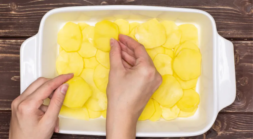 Картофель для этого рецепта нужно тонко нарезать и выложить в форму, застеленную пергаментом
