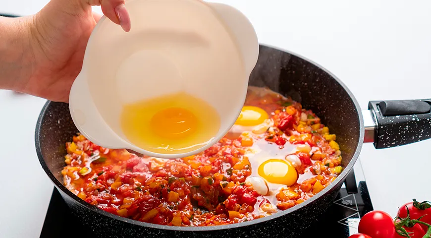 Перед тем как разбивать яйца, аккуратно сделайте в соусе небольшие углубления — так белок не растечется по всей сковороде,