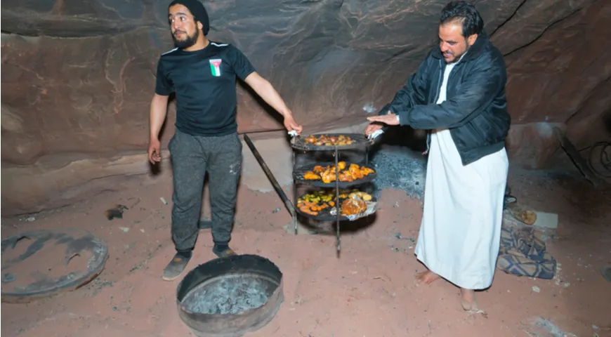 Арабы переносят металлическую «этажерку» с готовым блюдом зарб, Иордания