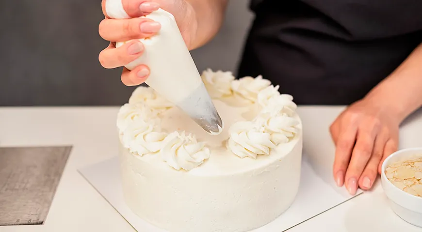 Украсить бисквитный торт можно кремом, используя кондитерский мешок с насадками