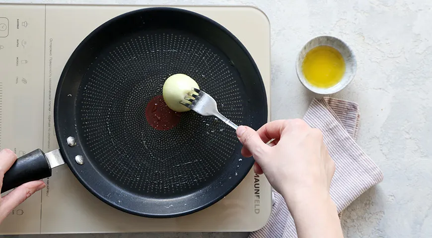 Смазывание сковороды маслом при помощи луковицы