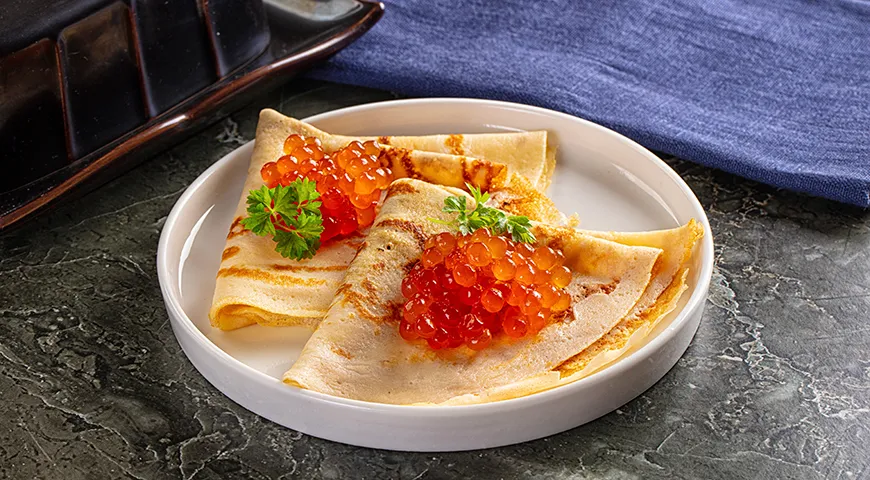 Подача икры кеты с блинами — это традиционный русский способ насладиться ее нежным вкусом