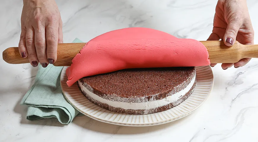 На торт предварительно раскатанную помадку переносят с помощью скалки