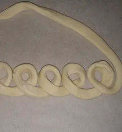 Режем тесто для пирога на жгуты и укладываем в форме петелек