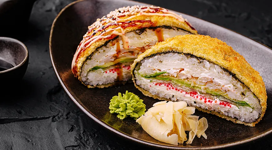Вкусные суши-роллы с хрустящей корочкой темпура подаются вместе с васаби и маринованным имбирем